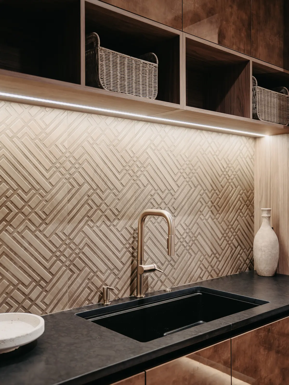 Patterned tile backsplash, brass faucet and black stone counter in a modern kitchen