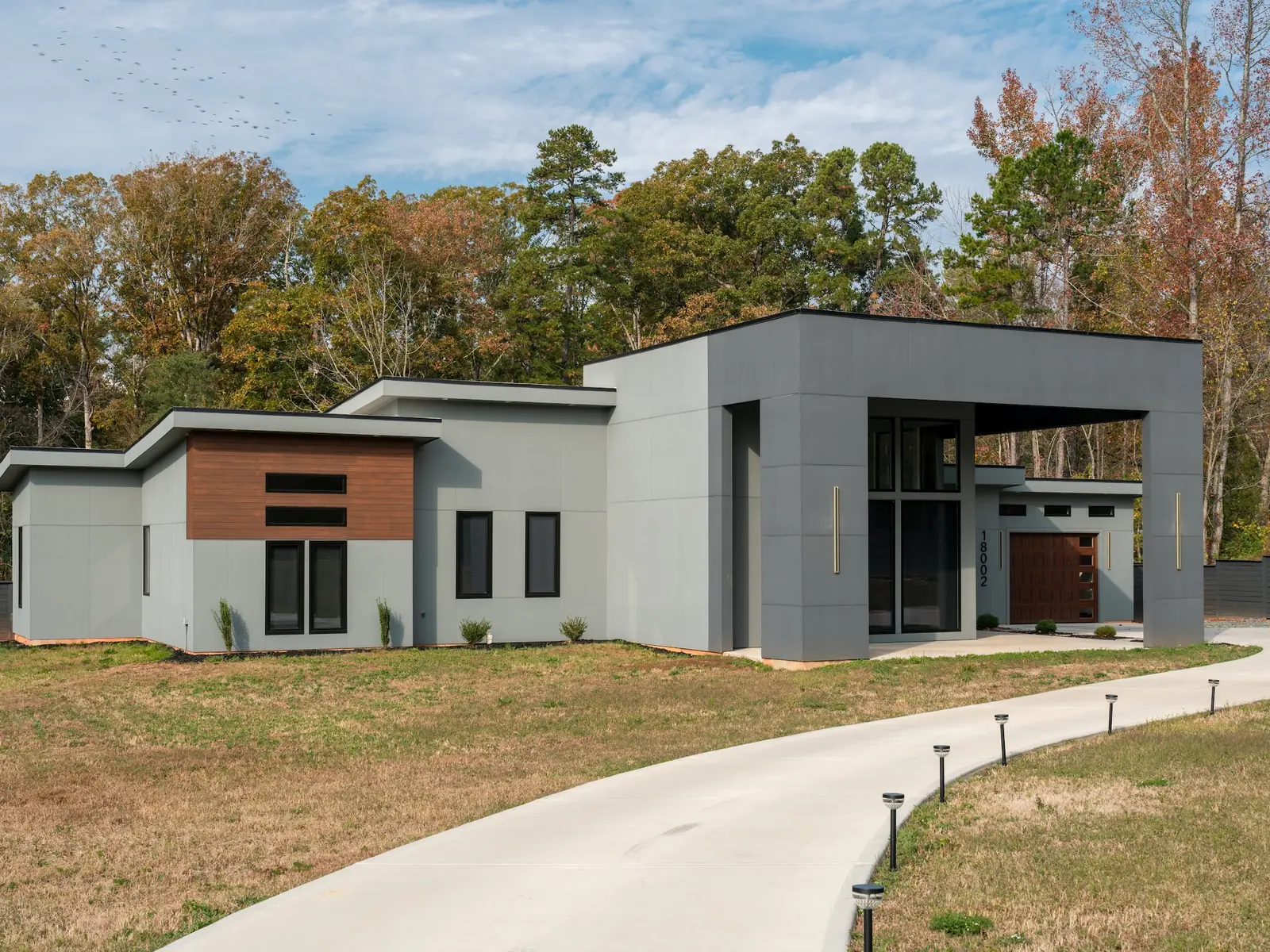 Modern single-story custom home in Charlotte, NC with a low roofline and brick facade